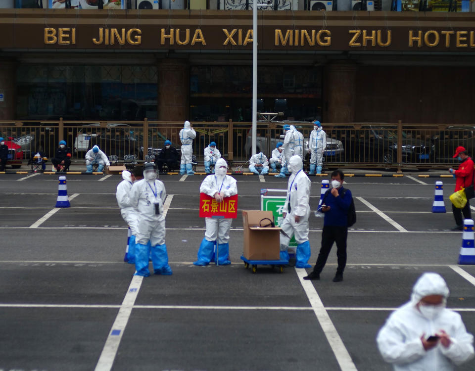 FILE - In this April 15, 2020, file photo, workers in full protective gear stand in a parking lot of the West Station in Beijing, China, as part of the team coordinating quarantine for incoming passengers from Wuhan. Getting into Wuhan was the easy part as new infections had fallen to almost zero and travel restrictions were relaxed. As a 76-day lockdown neared its end, journalists were allowed to return to the Chinese city where the coronavirus pandemic originated. But getting out was proving harder. The bureaucracy had yet to finalize how people would safely organize their return and three official documents were needed: A green health code, home neighborhood approval and a recent nucleic acid test. (AP Photo/Sam McNeil, File)