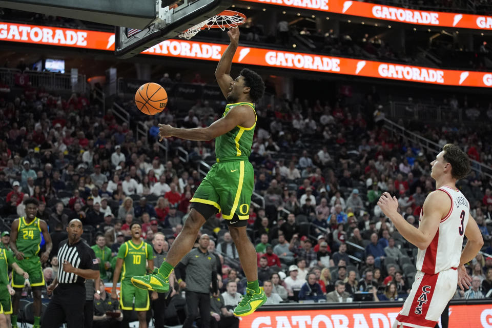Oregon guard Kario Oquendo (0) dunks over Arizona guard Pelle Larsson (3) during the second half of an NCAA college basketball game in the semifinal round of the Pac-12 tournament Friday, March 15, 2024, in Las Vegas. (AP Photo/John Locher)
