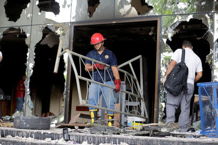 Firefighters remove debris from the building of the Congress, which was damaged after a demonstration against a proposed amendment that would allow Paraguay's president to stand for re-election, in Asuncion, Paraguay April 4, 2017. REUTERS/Jorge Adorno