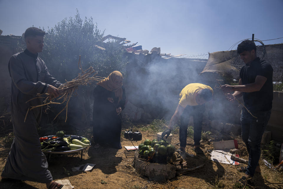 A group of Palestinian friends cook watermelons as they prepare to make "Lasima," at a garden in Khuzaa, Gaza Strip, Saturday, May 20, 2023. Palestinians in the southern Gaza Strip call it “watermelon salad.” But this delicacy popular in the area at this time of year is far from the sweet, refreshing taste the name evokes. (AP Photo/Fatima Shbair)
