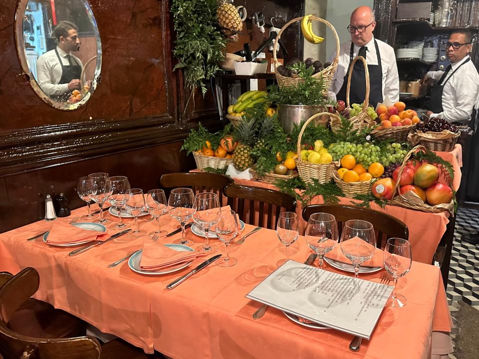 Coral table at Chez L'Ami Louis in front of large display of produce in baskets