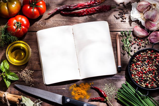 <p>Getty</p> Stock image of worn cookbook sin the middle of different ingredients and kitchen utensils