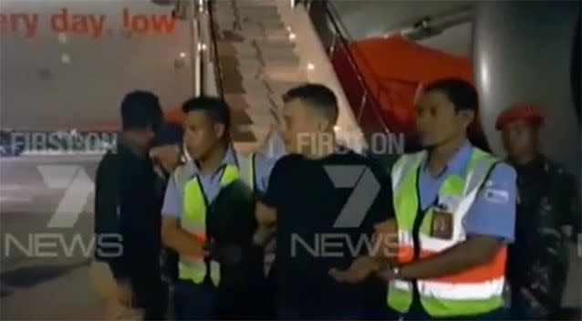 The men were escorted off the plane in Denpasar. Photo: 7 News