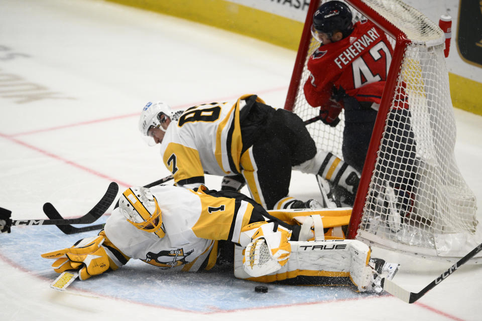 Washington Capitals defenseman Martin Fehervary (42) crashes into the Pittsburgh Penguins net along with Penguins center Sidney Crosby (87) during the third period of an NHL hockey game, Thursday, Jan. 26, 2023, in Washington. Penguins goaltender Casey DeSmith (1) lies on the ice. (AP Photo/Nick Wass)
