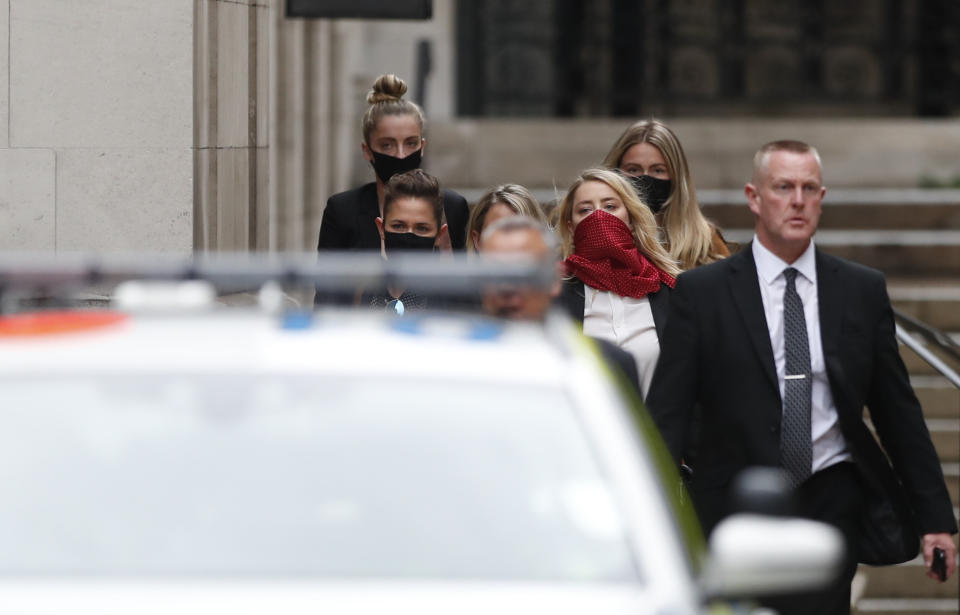 Amber Heard, con un pañuelo rojo sobre el rostro, sale del tribunal superior en Londres el jueves 9 de julio de 2020. Johnny Depp demandó a News Group Newspapers, empresa editorial del diario The Sun, y al editor ejecutivo del diario Dan Wootton por difamación por un artículo de 2018 que señalaba que abusó físicamente de su exesposa Amber Heard. Depp niega estas acusaciones. (Foto AP/Alastair Grant)