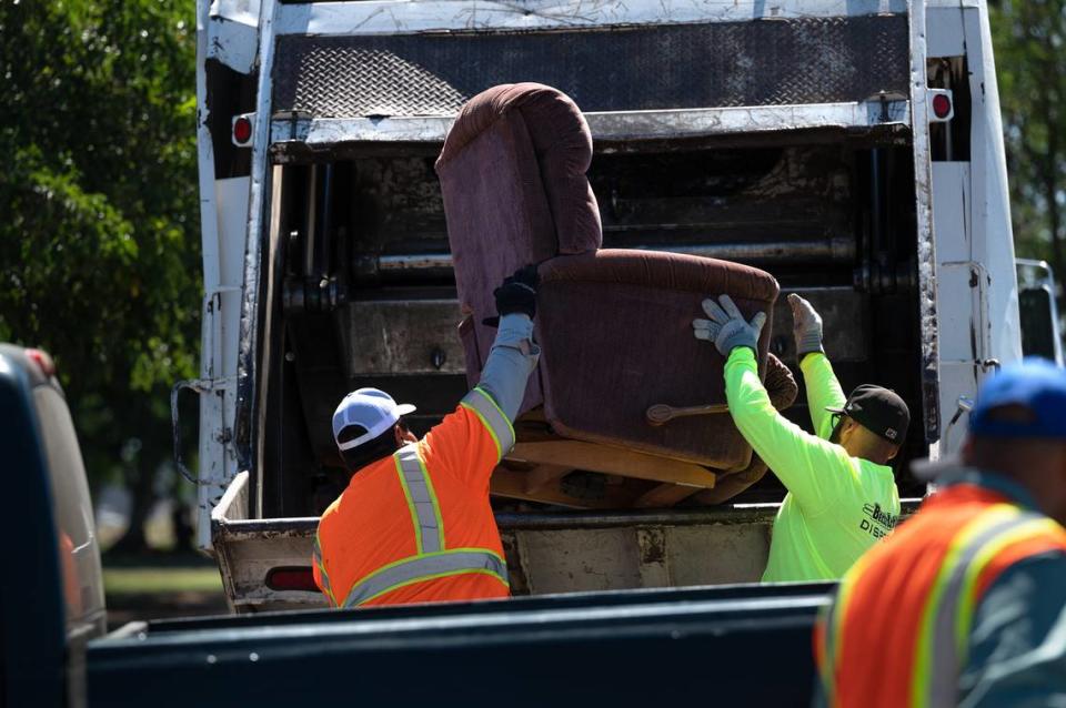 Workers from Bertolotti Disposal toss household items during a Modesto city sponsored trash day at John Thurman Field in Modesto, Calif., on Saturday, June, 25, 2022.