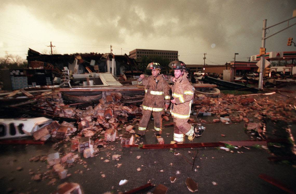 Firefighters survey destruction of the Color Wheel paint store along West Seventh Street in Fort Worth after a tornado struck on March 28, 2000.