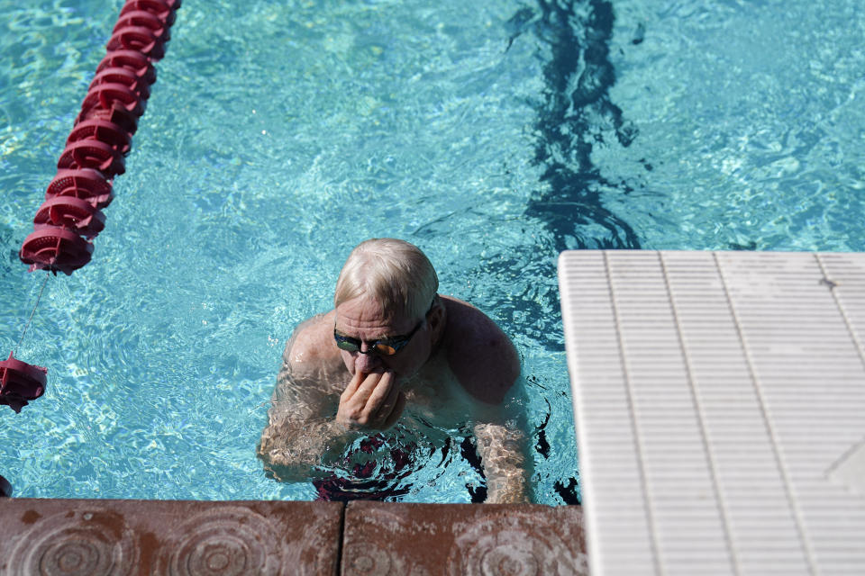 A senior swimmer clears his nose as he cools off in hot weather, Wednesday, July 19, 2023, in Pasadena, Calif. (AP Photo/Ryan Sun)