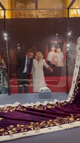 <p>The Royal Family Instagram</p> Queen Camilla studies a detail on the coronation robes at Buckingham Palace.