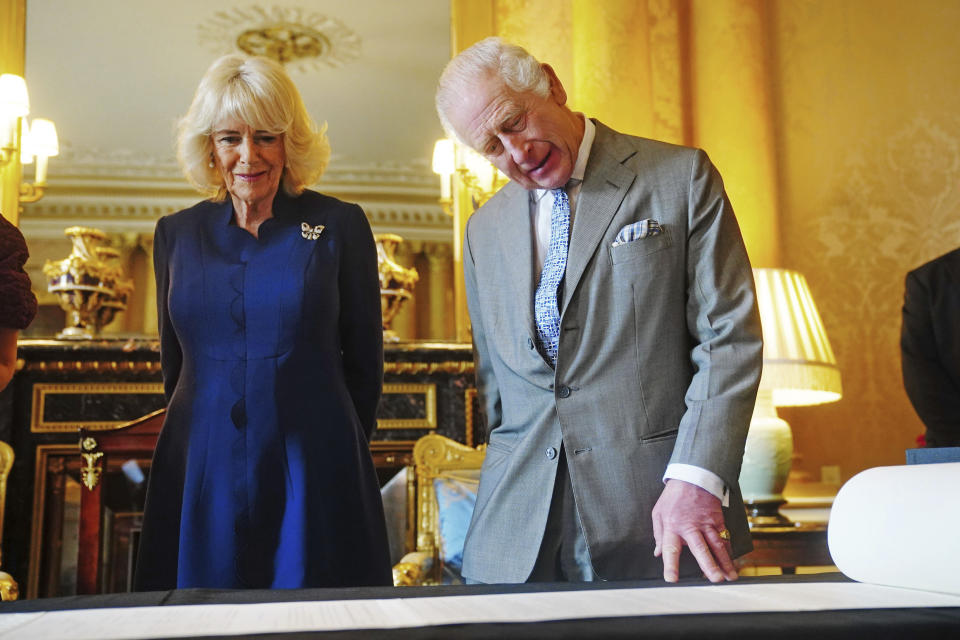 King Charles III and Queen Camilla are presented with the Coronation Roll, an official record of their Coronation, by the Clerk of the Crown in Chancery, at Buckingham Palace, central London, Wednesday May 1, 2024. King Charles III gaped at the 70-foot-long (21.4-meter) hand-lettered scroll as it was presented to him earlier this week at Buckingham Palace, thanking the artisans who produced the document that serves as the official record of his coronation almost a year ago. (Victoria Jones/PA via AP)