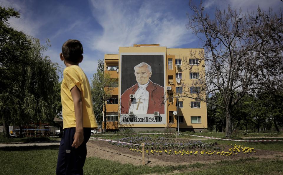 In this photo taken on Wednesday, May 1, 2019, a boy looks at a portrait of Pope John Paul II painted on an apartment block, reminiscent of his visit in 2002, in the town of Rakovsky, central Bulgaria, ahead of an upcoming visit by Pope Francis. During his first visit to the Orthodox country of Bulgaria, on May 5 and 6, Pope Francis will visit the capital, Sofia, and the town of Rakovsky, which is home of the largest Catholic community in the Balkan country. (AP Photo/Valentina Petrova)