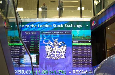 Workers speak above an electronic information board at the London Stock Exchange in the City of London January 2, 2013. REUTERS/Paul Hackett