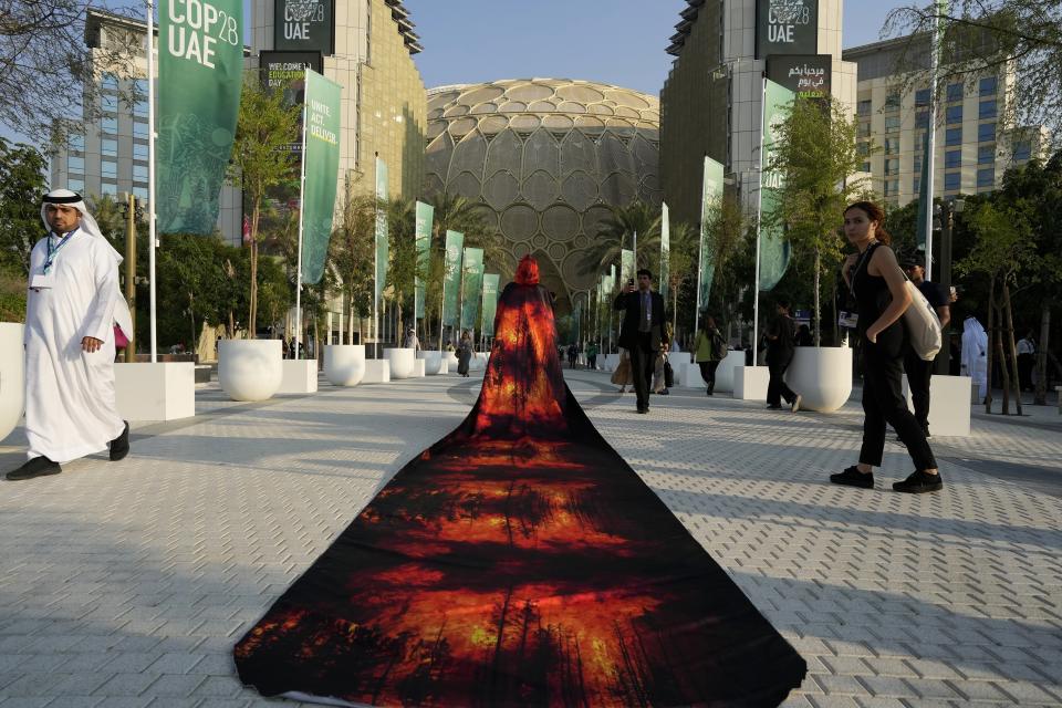 Islene Facanha, of Portugal, participates in a demonstration dressed with images of wildfires at the COP28 U.N. Climate Summit, Friday, Dec. 8, 2023, in Dubai, United Arab Emirates. (AP Photo/Peter Dejong)