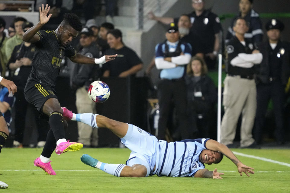 Sporting Kansas City defender Logan Ndenbe, right, falls as he battles with Los Angeles FC midfielder Jose Cifuentes during the first half of a Major League Soccer match Wednesday, May 17, 2023, in Los Angeles. (AP Photo/Mark J. Terrill)