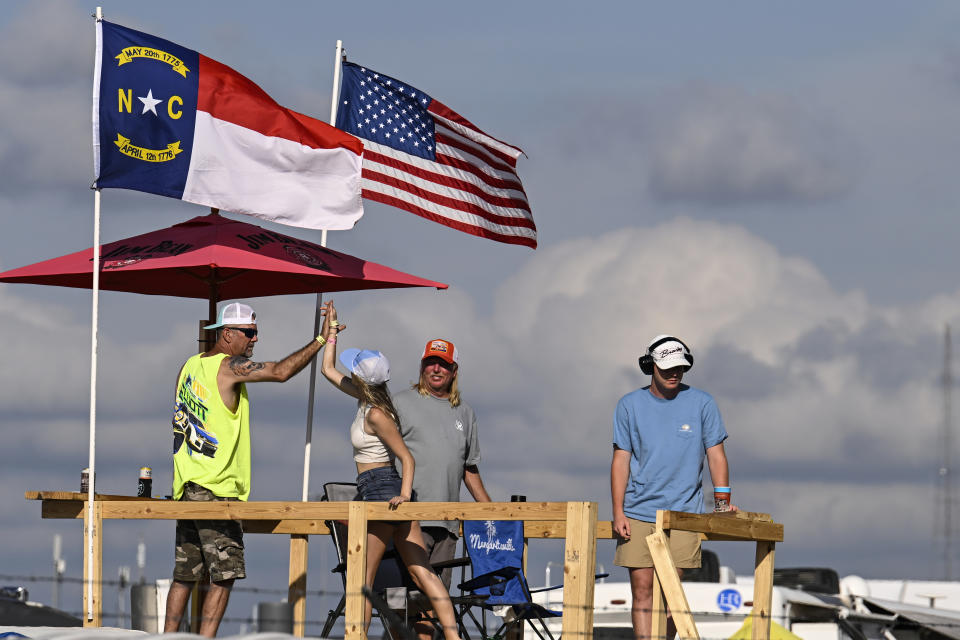 Two fans high-five during a NASCAR Cup Series auto race at Darlington Raceway, Sunday, May 14, 2023, in Darlington, S.C. (AP Photo/Matt Kelley)