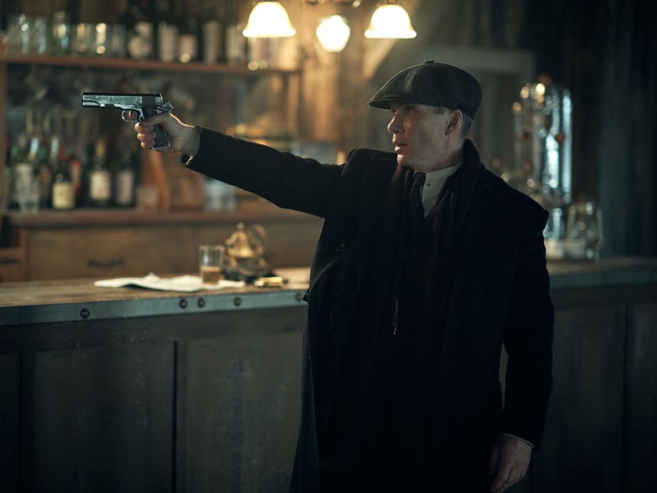 Man holding a gun in a bar in "Peaky Blinders"