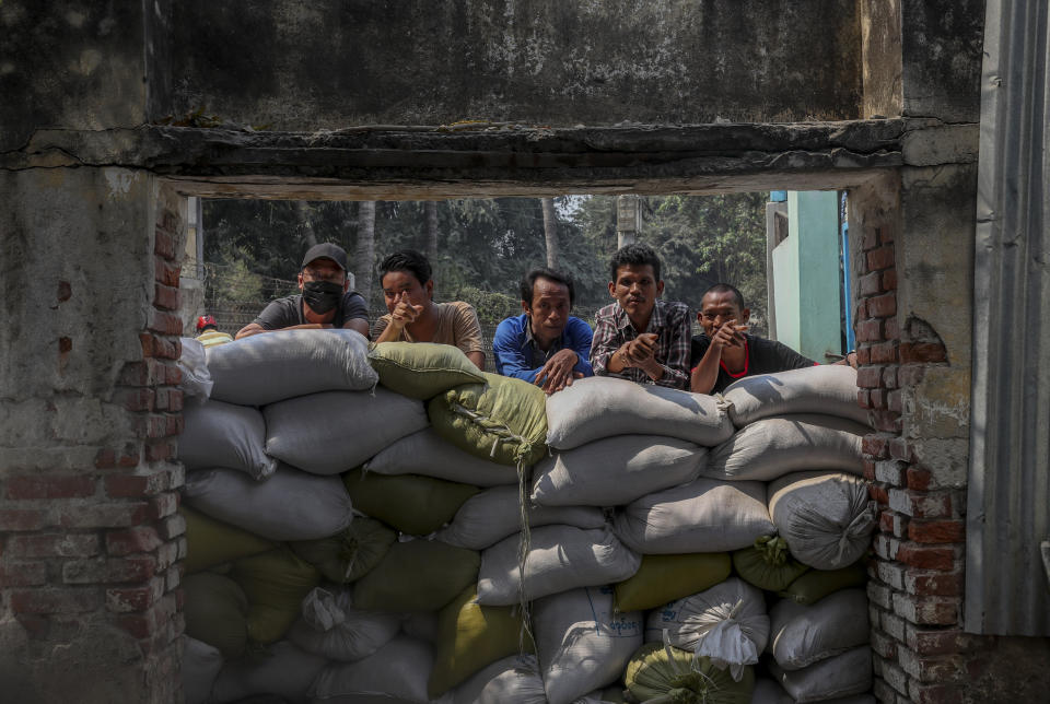 People watch as a convoy of soldiers and policemen arrive with bulldozers to remove makeshift barricades made by anti-coup protesters in Mandalay, Myanmar, Tuesday, March 9, 2021. Demonstrators in Myanmar's biggest city came out Monday night for their first mass protests in defiance of an 8 p.m. curfew, seeking to show support for an estimated 200 students trapped by security forces in a small area of one neighborhood. (AP Photo)