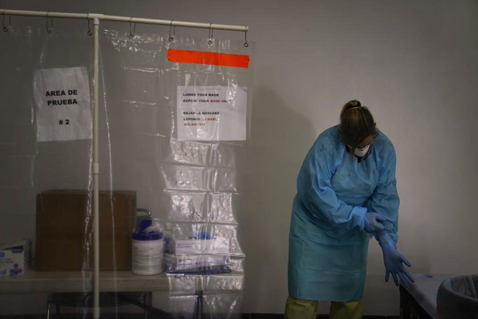 Registered nurse Leslie Clark puts on a new pair of protective gloves after collecting a nasal swab sample at a COVID-19 testing site in Los Angeles, Sunday, Dec. 27, 2020. Hospitals in central and Southern California are quickly running out of intensive care unit beds for coronavirus patients and state officials are poised to extend the strictest stay-at-home orders there as conditions worsen before the post-holiday surge hits. (AP Photo/Jae C. Hong)