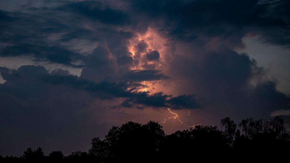 Über Berlin blitzt es hinter dunklen Wolken.