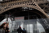 People walk past a screen announcing the closure of the Eiffel Tower after the French government banned all gatherings of over 100 people to limit the spread of the virus COVID-19, in Paris, Saturday, March 14, 2020. For most people, the new coronavirus causes only mild or moderate symptoms. For some it can cause more severe illness, especially in older adults and people with existing health problems. (AP Photo/Christophe Ena)