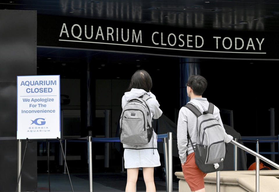 Visitors stand outside Georgia Aquarium after they found out it closed, Saturday, June 1, 2024, in Atlanta. City officials were slowly repressuring the city's water system Saturday after corroding water pipes burst in downtown and Midtown, forcing many businesses and attractions to close and affecting water service in area homes. (Hyosub Shin/Atlanta Journal-Constitution via AP)