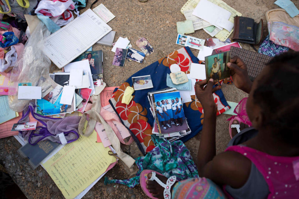 <p>After drying them in the sun, a young girl gathers her family photos that were soaked by Hurricane Matthew’s heavy rains, in Jeremie, Haiti, Friday, Oct. 7, 2016. (AP Photo/Dieu Nalio Chery)</p>