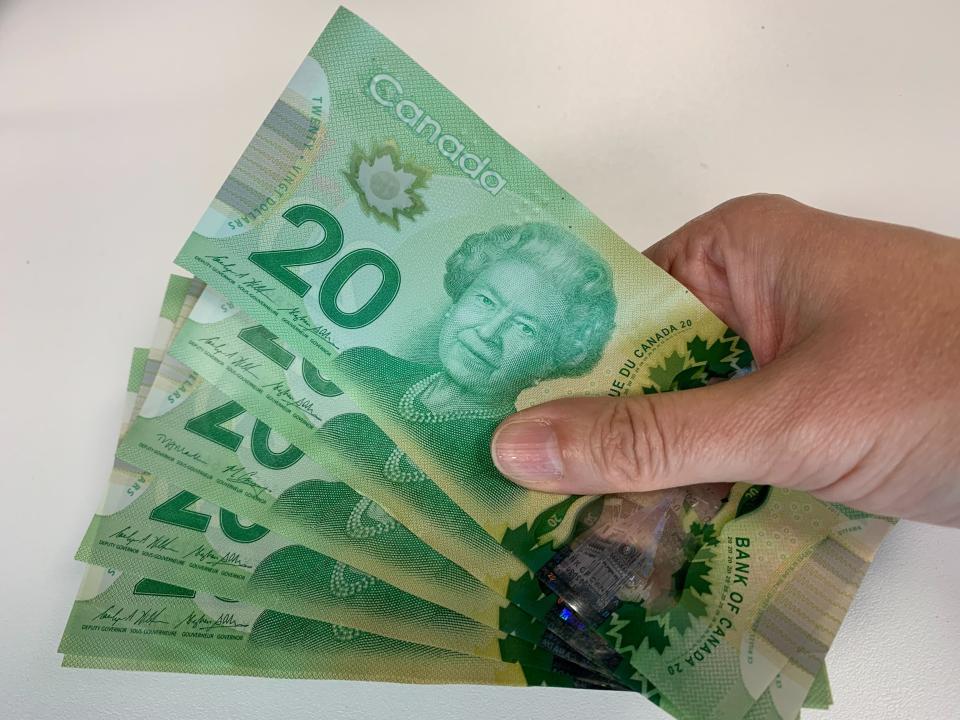 Canadian $20 bills are pictured in Toronto, Friday, Sept.9, 2022. As the United Kingdom's reigning monarch, Queen Elizabeth II was depicted on British bank notes and coins for decades. It's less well known that her portrait was featured on currencies in dozens of other places around the world, in a reminder of the British empire's colonial reach. (The Canadian Press via AP)