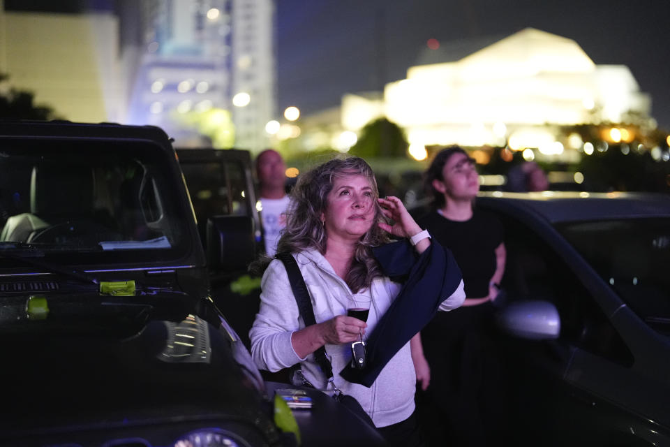 Vanessa Soteldo listens to a simultaneous translation into Spanish on her cell phone as she watches the first general election debate of the 2024 season between U.S. President Joe Biden and his Republican rival, former President Donald Trump, on a giant outdoor screen at the Nite Owl drive-in theater, Thursday, June 27, 2024, in Cape Coral. The viewing party at Miami's Nite Owl drive-in theater was organized by the Biden-Harris campaign and the Florida Democratic Party. (AP Photo/Rebecca Blackwell)