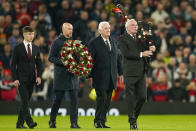 Manchester United's head coach Erik ten Hag, second left, with Alexander Stepney English former player, second right, and Manchester United academy player Dan Gore lays flowers in memory of Sir Bobby Charlton prior the Champions League group A soccer match between Manchester United and Copenhagen at the Old Trafford stadium in Manchester, England, Tuesday, Oct. 24, 2023. (AP Photo/Dave Thompson)