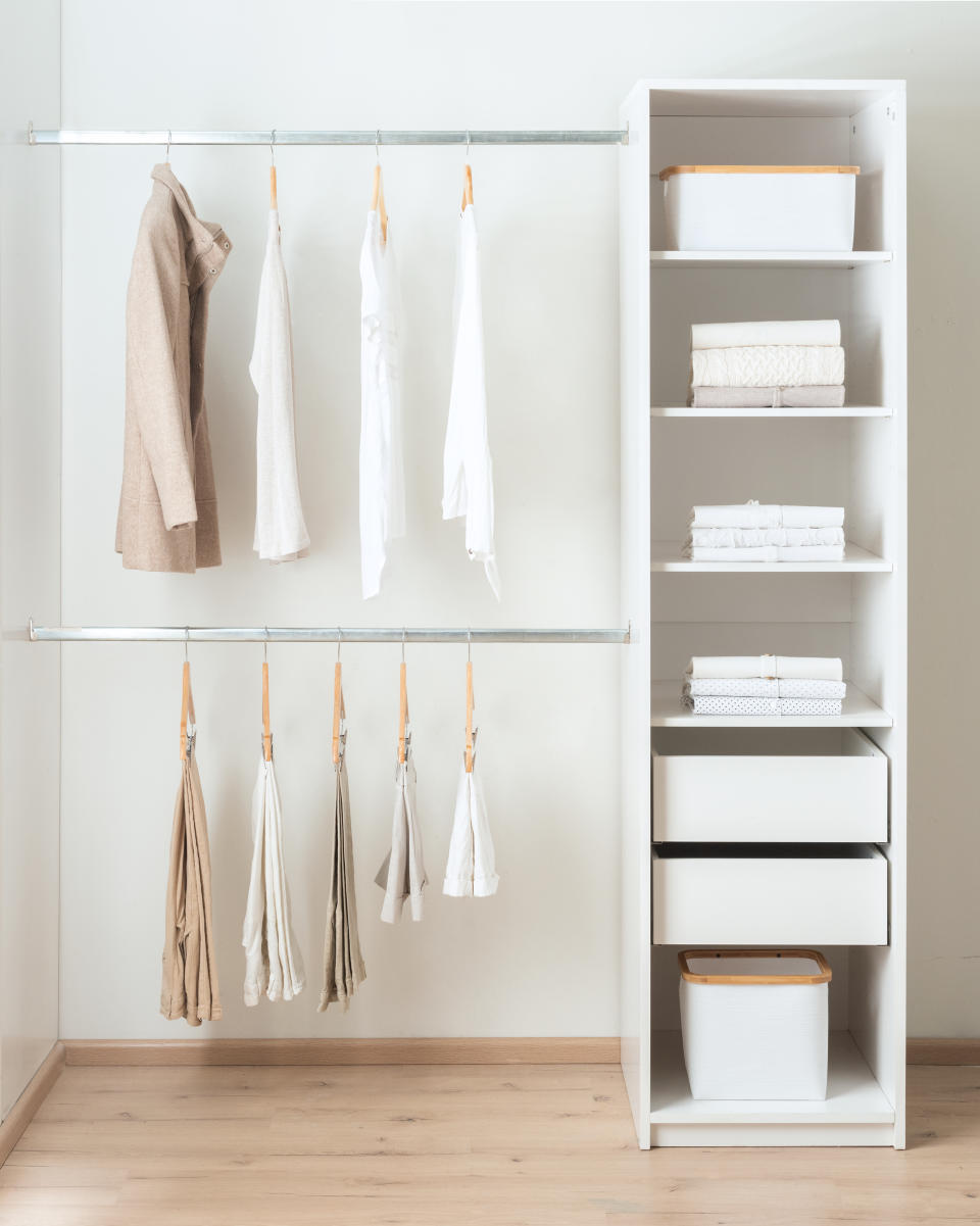 Clothes hanging neatly on a clothing rack on the left and shelves with towels and storage on the right