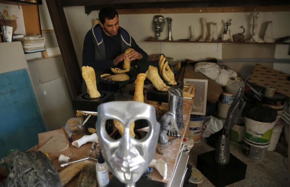 In this Tuesday, March 14, 2017 photo, Palestinian artist Mohammed Abu Hashish, 28, shapes limbs in his small workshop in a refugee camp in the central Gaza Strip. The artist is crafting art out of honeycomb to draw attention to Palestinians who lost limbs in fighting with Israel. (AP Photo/Hatem Moussa)