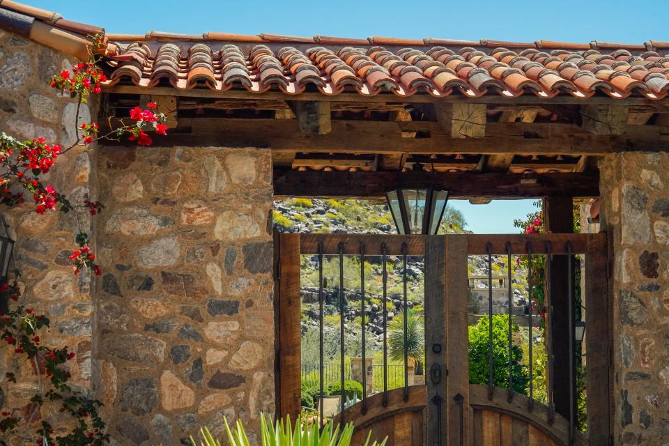 A stone house with a gate and mountains visible through the bars