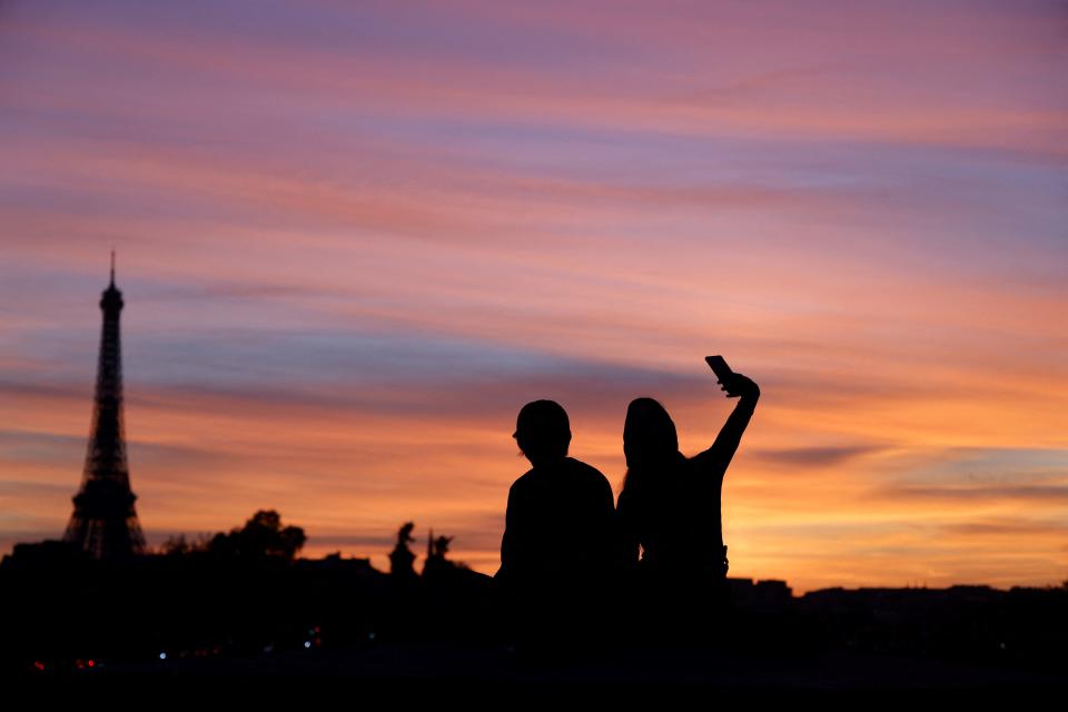 FTSE  People make selfie near the Eiffel tower at sunset in Paris, on October 3, 2022. (Photo by Ludovic MARIN / AFP) (Photo by LUDOVIC MARIN/AFP via Getty Images)