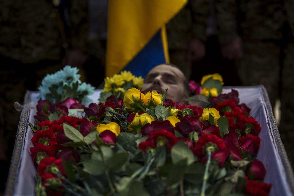 Flowers cover the body of Ukrainian serviceman Vadym Popelniuk, born in 1991, during a religious service in Independence Square in Kyiv, Ukraine, Friday, April 5, 2024. (AP Photo/Vadim Ghirda)