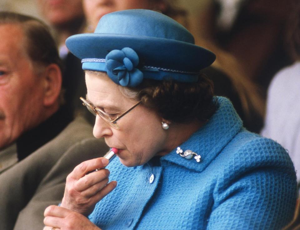 Queen Elizabeth II putting on lipstick