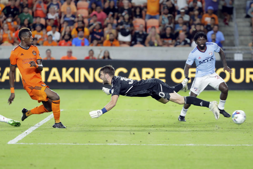 Houston Dynamo defender Teenage Hadebe, left, gets his shot past FC Dallas goalkeeper Maarten Paes, center, to score as FC Dallas midfielder Ema Twumasi, right, looks on during the second half of an MLS soccer match Saturday, July 9, 2022, in Houston. (AP Photo/Michael Wyke)