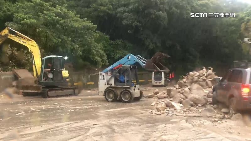 新工處人員用鏟裝機及挖土機清除道路中央的石塊。