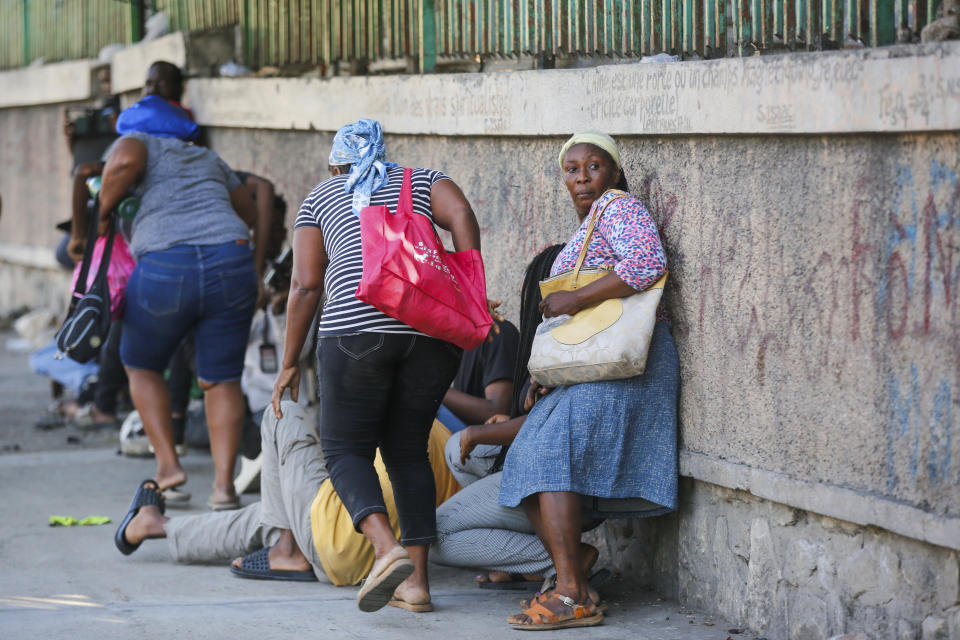 Pedestrians take cover during clashes between police and gang members in Port-au-Prince, Haiti, Friday, March 1, 2024. (AP Photo/Odelyn Joseph)