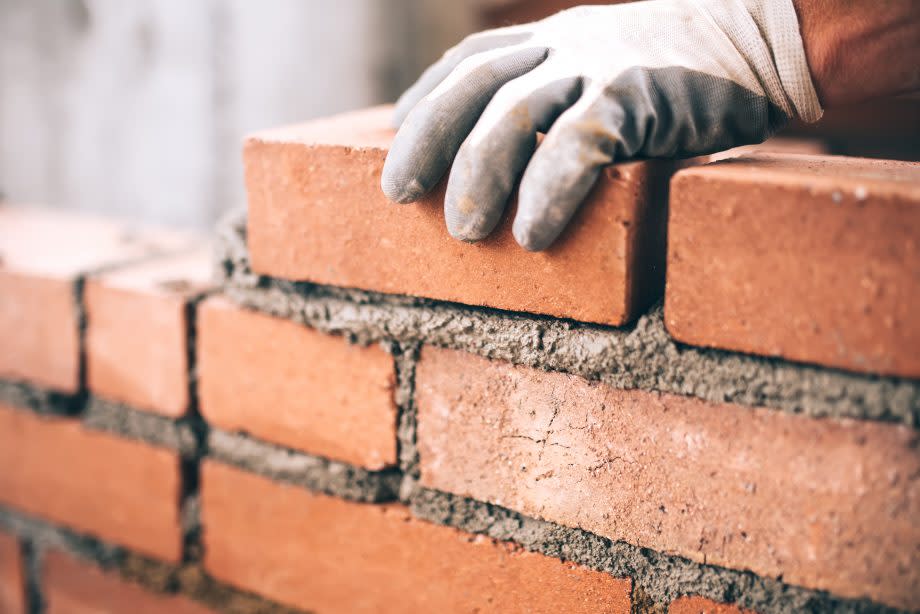 Mensch baut Mauer aus Ziegelsteinen