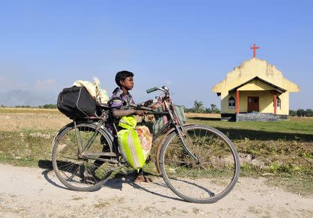 A boy transports his belongings on a bicycle as he moves to a safer place after ethnic clashes in Tenganala village, in Sonitpur district in the northeastern Indian state of Assam on December 24, 2014. REUTERS/Stringer