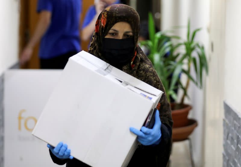 FILE PHOTO: A woman carries a box containing food from FoodBlessed, as the spread of the coronavirus disease (COVID-19) continues, in Beirut