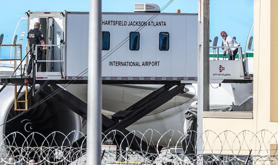 A Customs and Border Protection officer meets a plane carrying 359 American and Canadian passengers from Costa Luminosa. Three people on the flight, which arrived in Atlanta Friday, have tested positive for coronavirus.