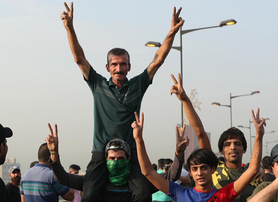 Anti-government protesters flash v-signs during a demonstration in central Baghdad, Iraq, Thursday, Oct. 3, 2019. Iraqi security forces fired live bullets and used tear gas against a few hundred protesters gathered in central Baghdad on Thursday, hours after a curfew was announced in the Iraqi capital on the heels of two days of deadly violence that gripped the country amid anti-government protests. (AP Photo/Hadi Mizban)