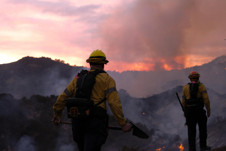 Firefighters keep watch as smoke rises from a brush fire scorching at least 100 acres in the Pacific Palisades area of Los Angeles, Saturday, May 15, 2021. (AP Photo/Ringo H.W. Chiu)