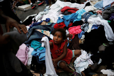 A girl from a homeless family that was living in a building that caught fire and collapsed in the center of Sao Paulo picks up clothes donated by well-wishers, next to a church at Largo do Painsandu Square in Sao Paulo, Brazil May 1, 2018. REUTERS/Nacho Doce