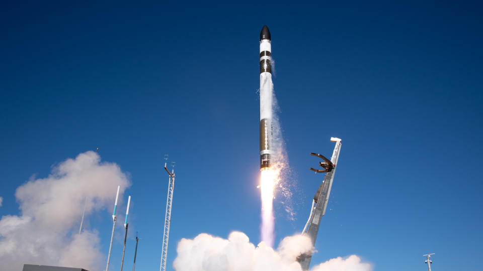 Eine weiß-schwarze Rakete startet in einen blauen Himmel.