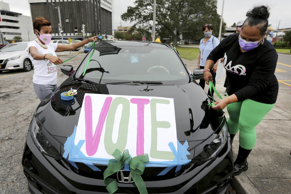 Maurya Glaude and Angela Davis decorate a car before a "Parade to the Polls" event, organized by Operation Go Vote!, a collaborative of African American civic and social organizations, in New Orleans, Saturday, Oct. 24, 2020. In the best of times, it’s a massive logistical challenge to get millions out to vote. In 2020, the difficulty has been dramatically compounded: by fear of the coronavirus, by complications and confusion over mail-in ballots, by palpable anxiety over the bitter divisions in the country. (AP Photo/Rusty Costanza)