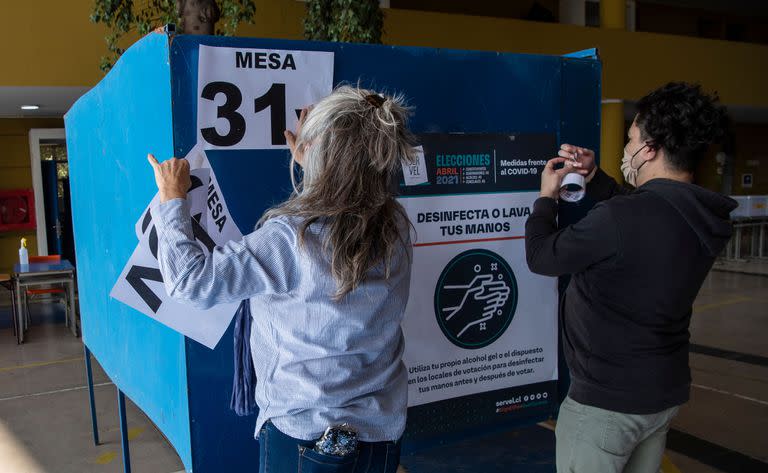 Empeados del servicio electoral instalan las mesas para de votación en una escuela de Santiago