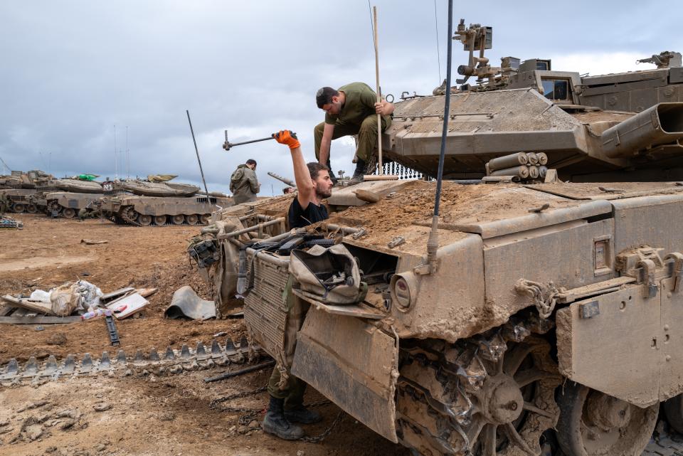 Members of the IDF work on a Merkava tank at a staging area near the border of Gaza as the ceasefire between Israel and members of Hamas holds for the release of prisoners and hostages on November 27, 2023, outside of the city of Sedero in Tel Aviv, Israel. <em>Photo by Spencer Platt/Getty Images</em>