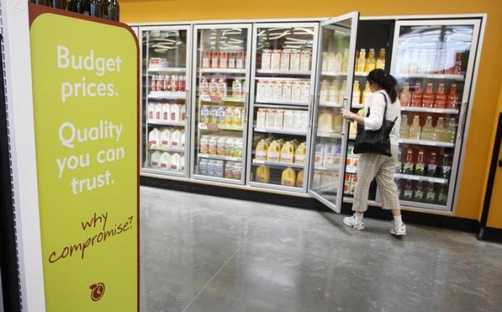 A sign promoting budget prices is seen as a shopper selects a bottle of juice inside a Tesco's Fresh & Easy Neighborhood Market food store in Compton, California, May 13, 2009. REUTERS/Danny Moloshok